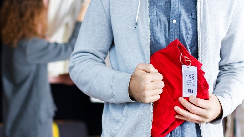 man shoplifting red jeans