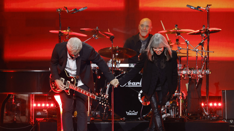 Neil Giraldo and Pat Benatar taking a bow onstage in 2022