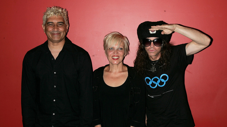 Pat Smear, Lorna Doom, and Don Bolles pose against red background