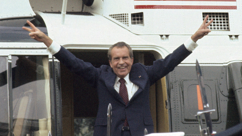 Richard Nixon boarding helicopter with arms outstretched