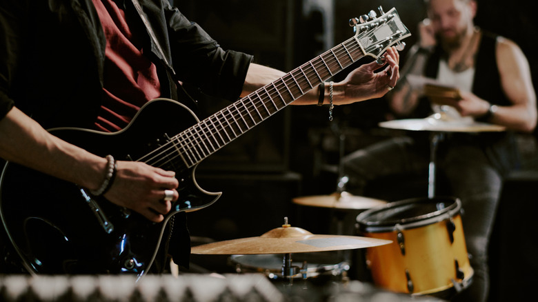 Musician tuning electric guitar with band