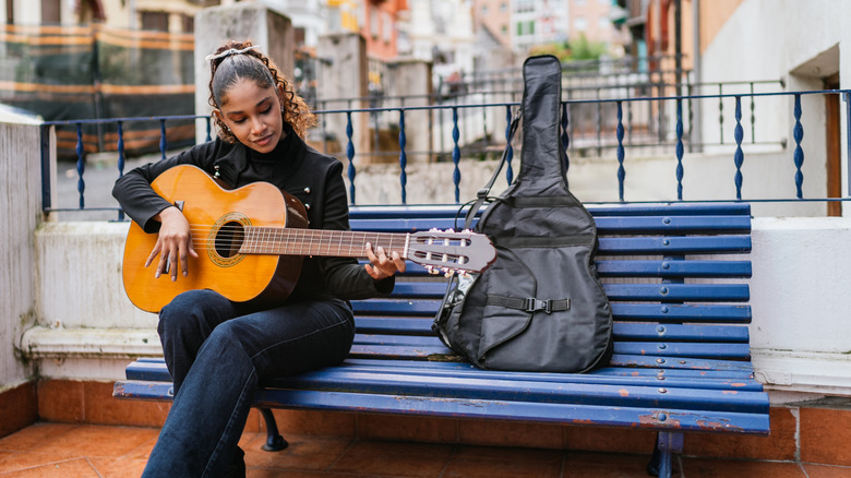 Girl playing guitar on bench