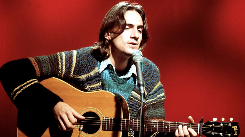 James Taylor singing and playing guitar with eyes closed