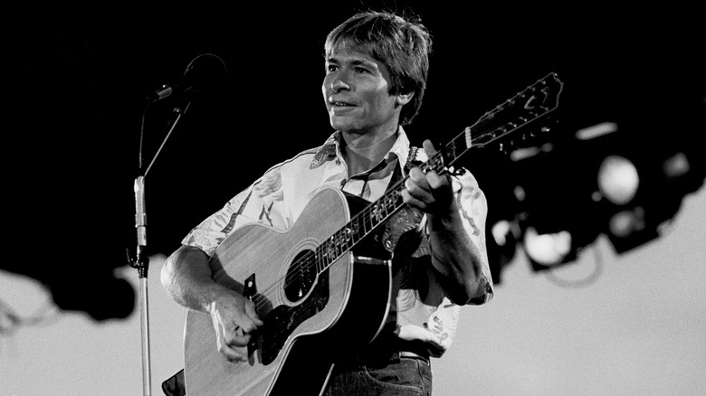 John Denver playing guitar on stage