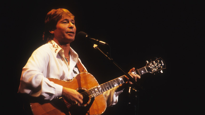 John Denver playing guitar and singing on stage