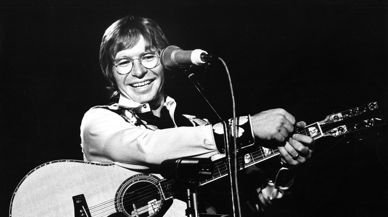 John Denver smiling with guitar and microphone