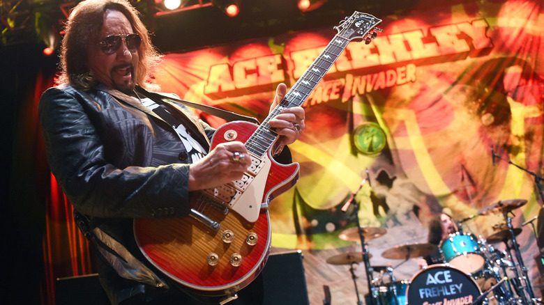 Ace Frehley performing on stage with drums in background