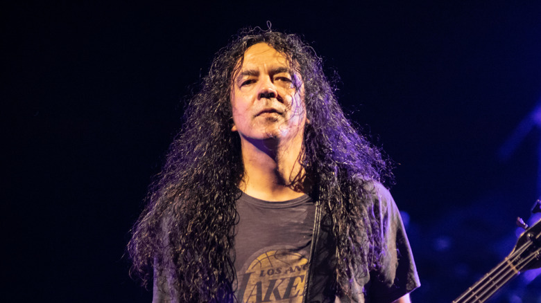 Mike Inez with long hair playing guitar on stage