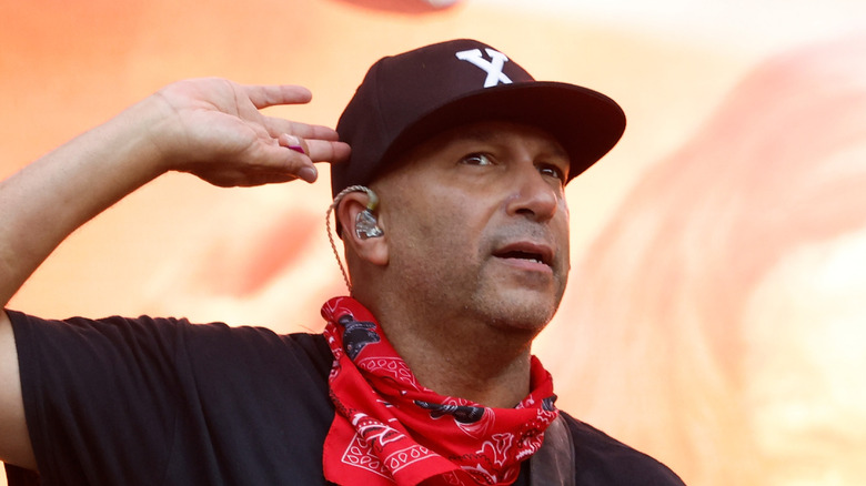 Tom Morello holding hand up to ear onstage