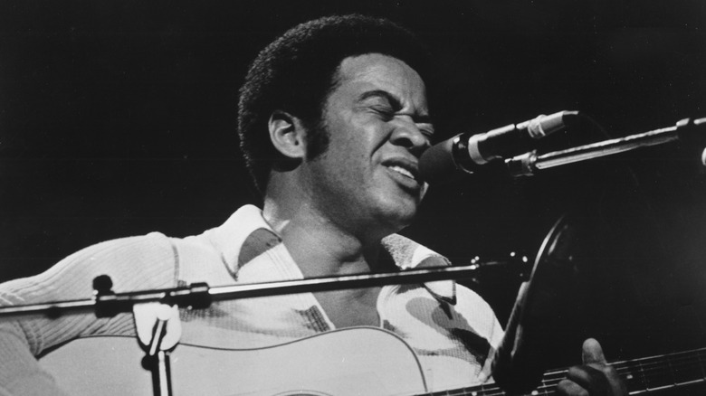 Bill Withers playing guitar and singing on stage