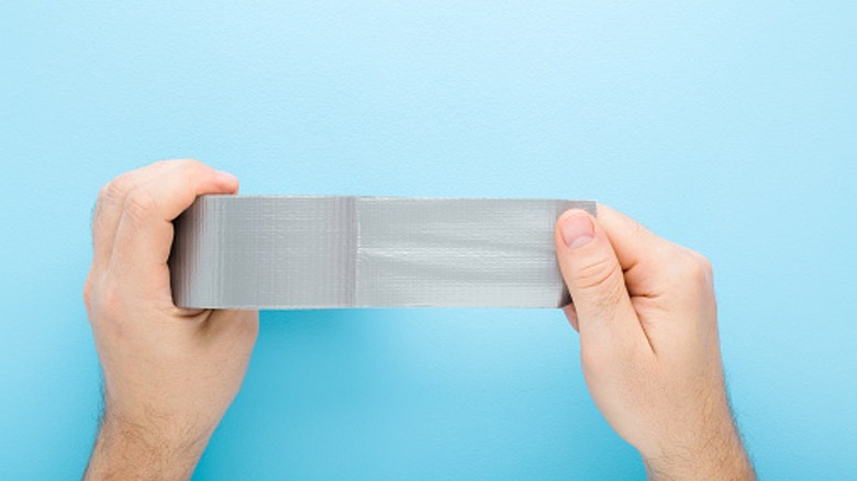 Man holding duct tape on blue background