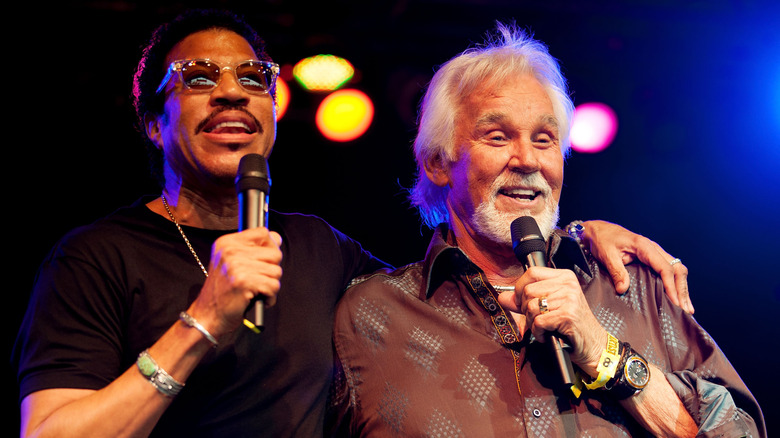 Lionel Richie and Kenny Loggins singing together on stage.