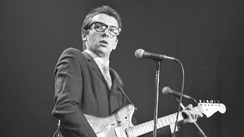 Elvis Costello holding a guitar onstage