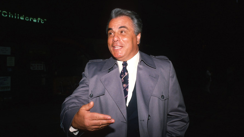 John Gotti gray trenchcoat smiling 