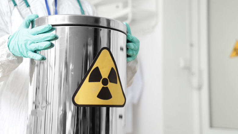 A scientist holding a radioactive container