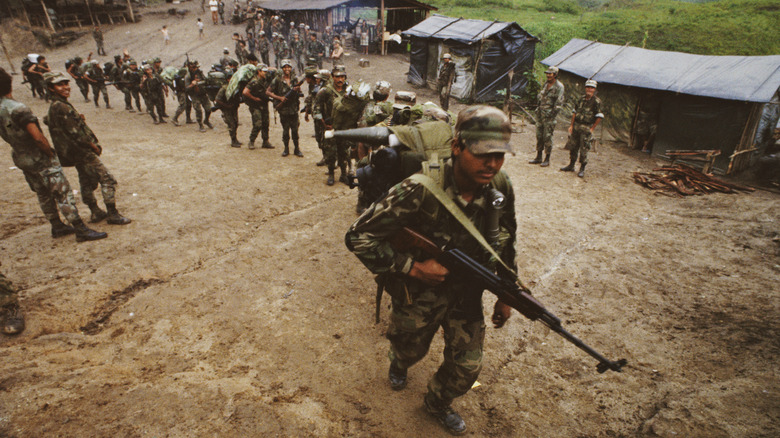 contra fighters with guns walking in line near tents
