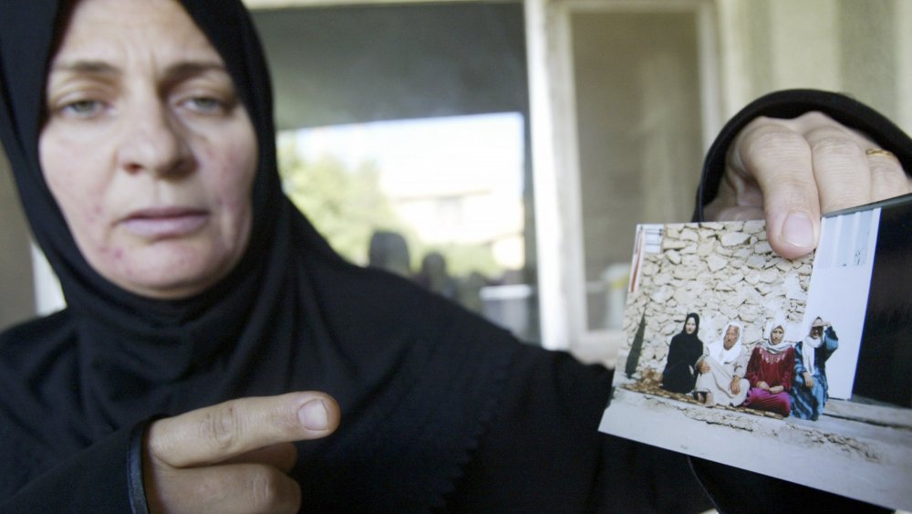 Iraqi woman holding a photo of her relatives killed by US Marines in 2005