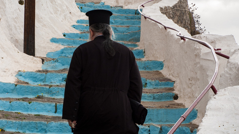 Eastern Orthodox monk climbing blue stairs