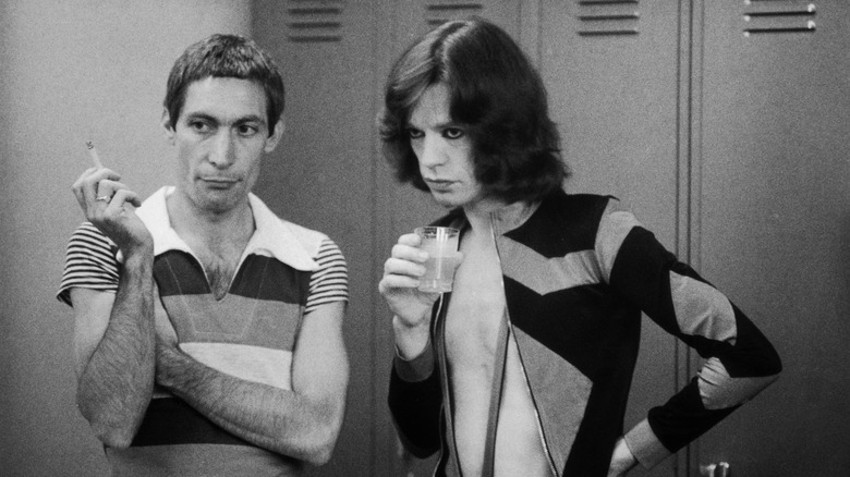 Charlie Watts with Mick Jagger in front of a row of lockers