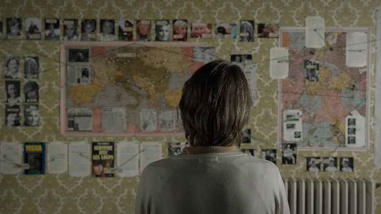 woman looking at investigatory material pinned to wall