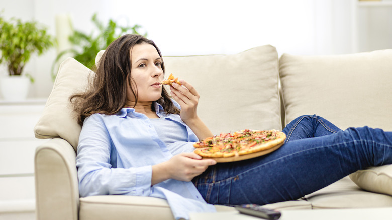 woman watching tv and eating pizza