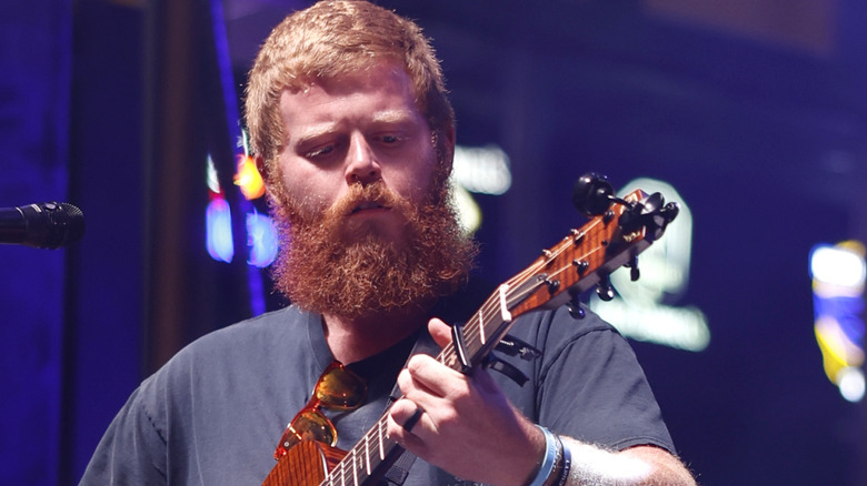 Oliver Anthony looking at guitar as he plays