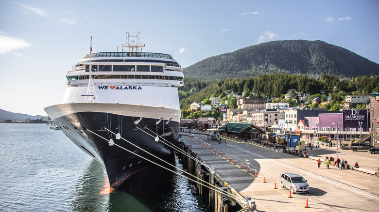 A cruise ship sails across the ocean at sunset with a vibrant orange and blue sky