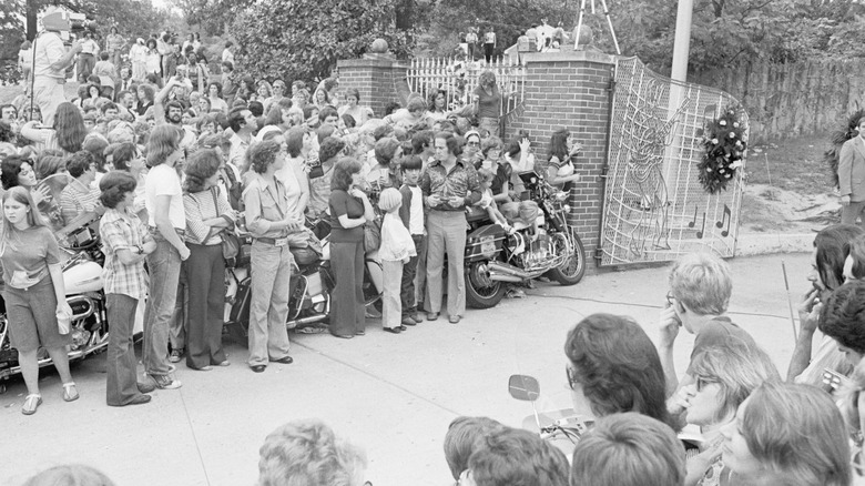 A large crowd of fans waiting outside the gates of Graceland to view Elvis's coffin