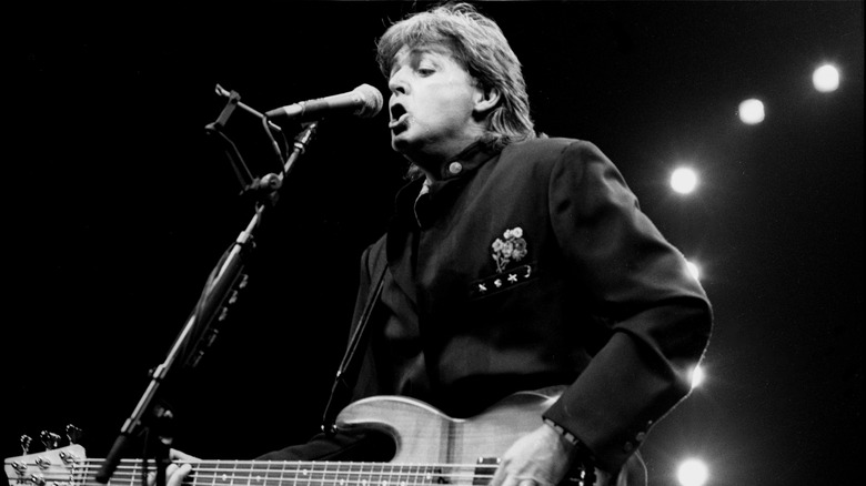 Paul McCartney singing into microphone while playing bass