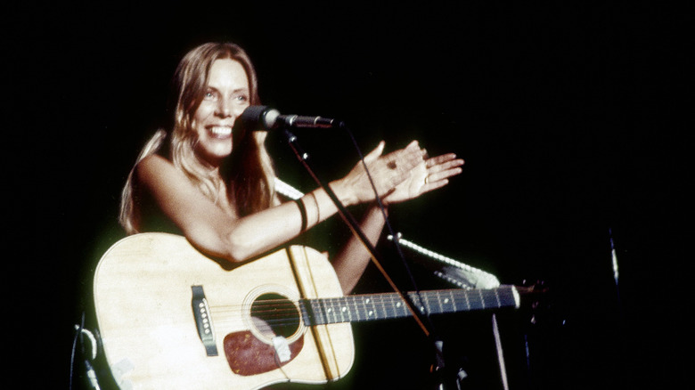 Joni Mitchell clapping with acoustic guitar onstage in California in 1974