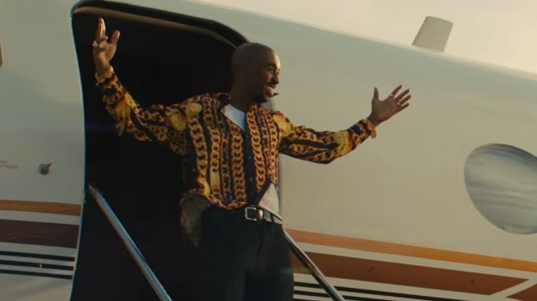 Tupac leaving plane smiling with arms up in still from All Eyez on Me