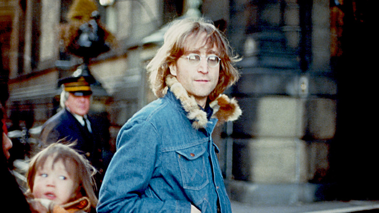 John Lennon in the street in denim jacket and glasses