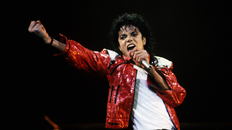 Michael Jackson in red jacket with microphone with fist raised