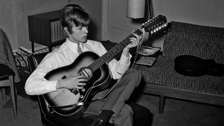 david bowie sitting in chair playing guitar 1966