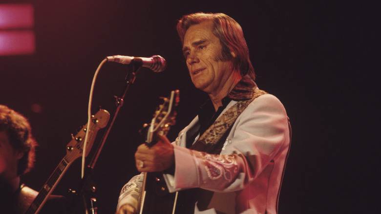 George Jones playing a guitar on stage
