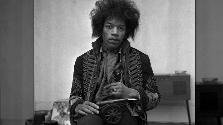 Jimi Hendrix in a martial-style coat holding a toy cannon