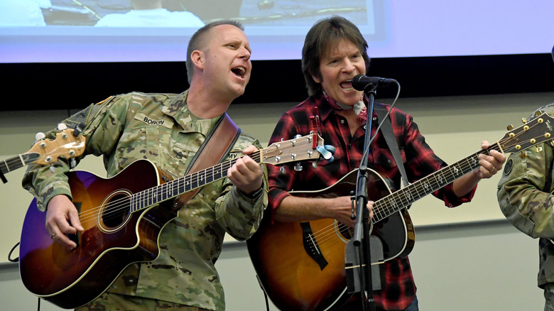 John Fogerty performing with several members of the military wearing camo