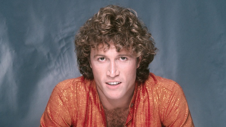 Andy Gibb posing in an orange shirt