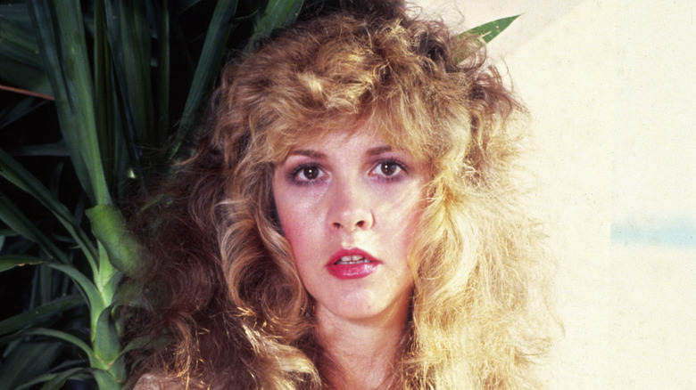 Stevie Nicks posing in front of plant