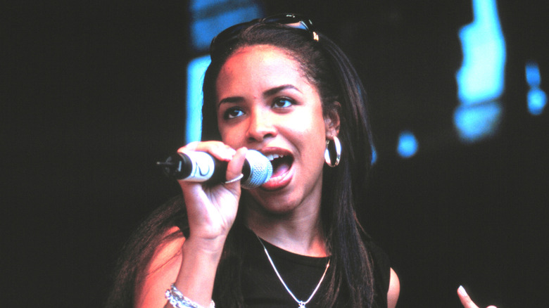 Aaliyah singing into mic on stage