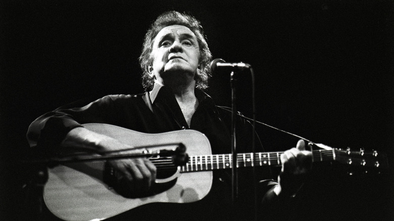 Johnny Cash playing guitar with dark background
