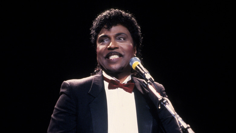 Little Richard in suit smiling at mic on stage