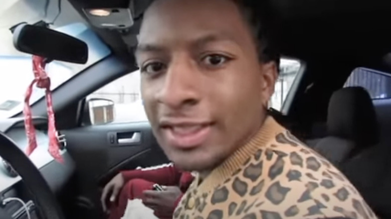 Young QC in car holding money talking to camera