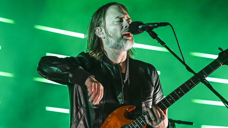 Thom Yorke playing guitar on stage in 2022