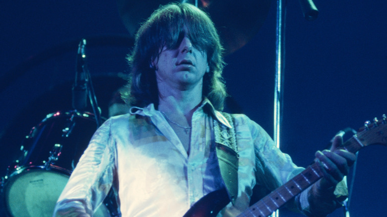 Mick Ralphs playing guitar onstage with hair covering eyes