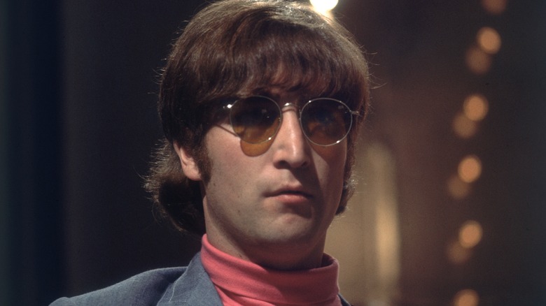 John Lennon wearing sunglasses and a pink turtleneck
