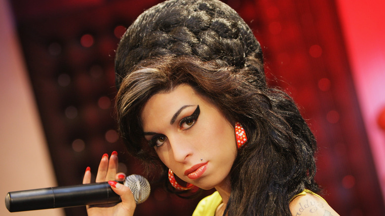 Amy Winehouse with beehive hair and makeup holding mic