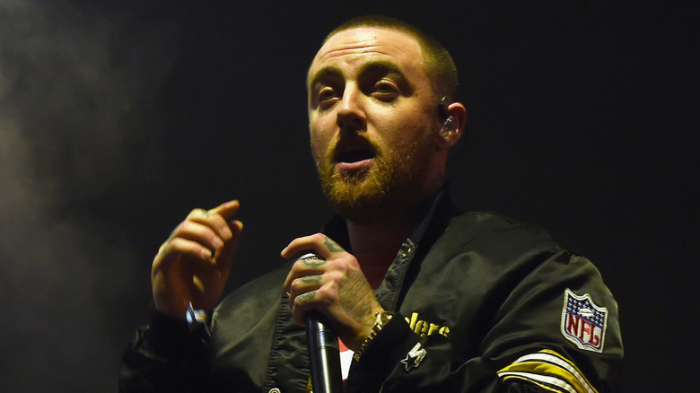 Mac Miller in NFL jacket singing into mic