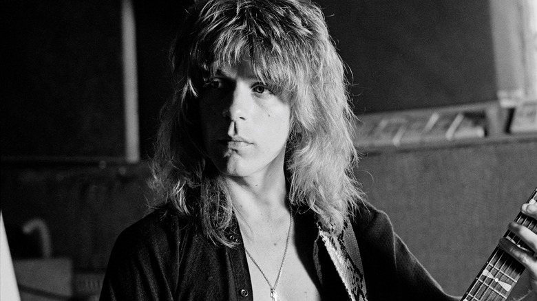 Randy Rhoads with long hair holding guitar