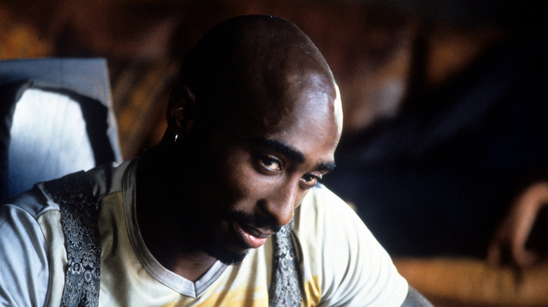 Tupac Shakur smiling with head down looking sideways